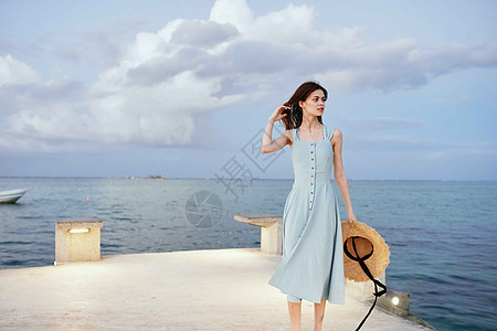 妇女在海滨附近穿着衣服 夏季休闲生活方式平衡自由喜悦日落女士晴天游客头发帽子女孩图片