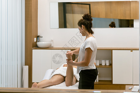 在美容院做腿按摩的中年妇女沙龙福利说谎护理脊椎治疗桌子肌肉理疗身体图片