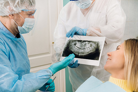 牙科医生向办公室的病人解释X光片的详细细节以及卫生卫生员牙科乐器药品女士讨论x光职业照片背景图片