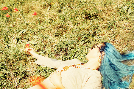 蓝背景上的花美丽的女人躺在花草地上背景