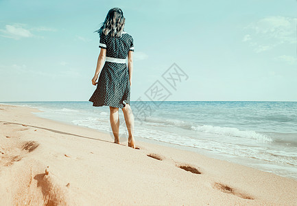 赤脚妇女走在沙滩上留下脚印图片