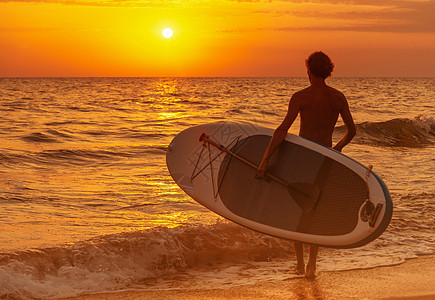有SUP牌的人 日落时会去海边图片