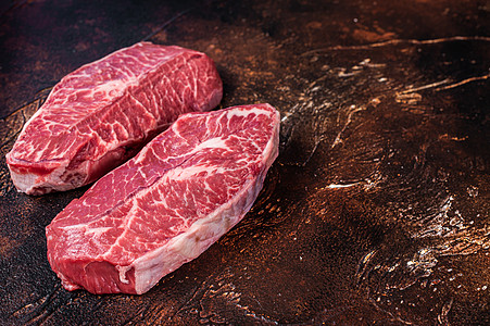Raw 顶顶刀片或肉食桌上的平板铁牛肉牛排 暗底背景 最上视图 复制空间图片