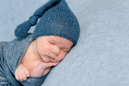 刚出生的婴儿男孩睡得很香蓝色生活童年毯子帽子皮肤男生孩子姿势襁褓图片