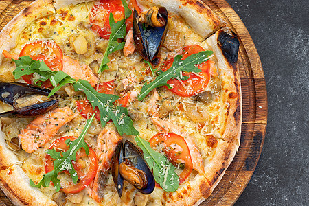 木板上的鲑鱼扇贝披萨和海鲜壳小吃厨房蔬菜午餐糕点香料面包草药胡椒餐厅图片