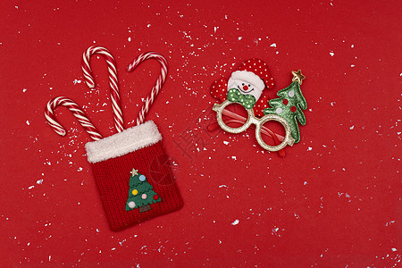 带糖果的圣诞红袋和带雪花的红色背景圣诞眼镜图片