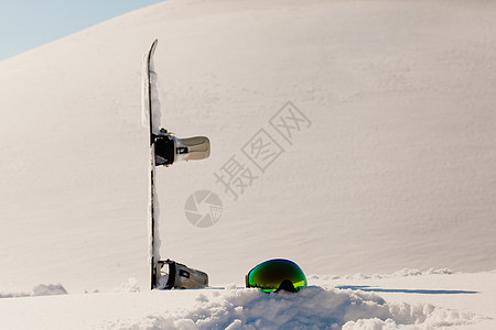 滑雪板和滑雪谷歌 在自由斜坡附近的雪上躺下太阳假期活动粉末反射踪迹天空乐趣木板旅行图片