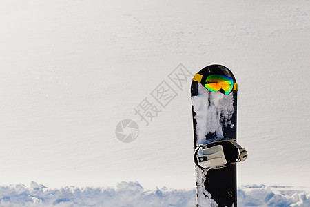 滑雪板和滑雪谷歌 在自由斜坡附近的雪上躺下蓝色阳光踪迹季节活动乐趣高山运动旅行反射图片