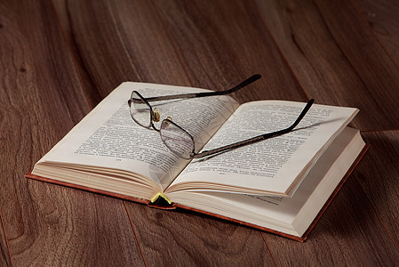 开着的书 上面有木木背景上的眼镜图片