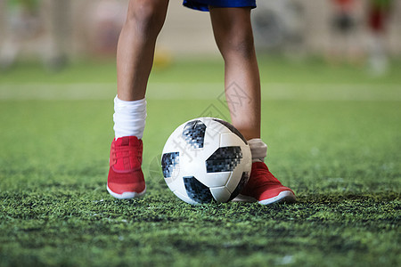 传统足球球在足球田草地上 有年轻运动员的脚图片