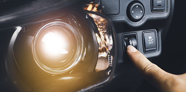 驾驶员手调节大灯电平开关和汽车大灯亮 双曝光汽车概念图片