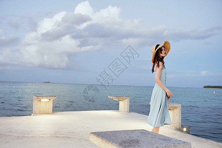妇女在海滨附近穿着衣服 夏季休闲生活方式休息女孩假期女性头发海洋帽子日落女士海滩图片