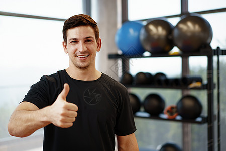 体育馆一位年轻英俊健身教练的肖像运动健美房间活动微笑男性运动员双臂快乐运动装图片