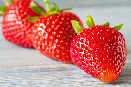 蓝木本底的新鲜成熟草莓 有选择的重点 特写木头水果甜点红色浆果蓝色饮食乡村桌子麻布图片