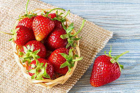 篮子里新鲜的成熟草莓和蓝木本底的薄饼 有选择的重点麻布红色浆果水果食物蓝色木头桌子乡村甜点图片