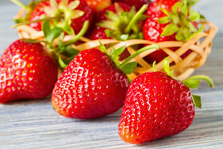 蓝木本底的新鲜成熟草莓 有选择的重点 特写桌子饮食蓝色浆果木头乡村红色麻布篮子甜点图片