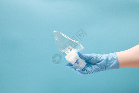 蓝色一次性医疗手套中的女性手握着含有硅胶面罩 吸入装置 肺学概念 蓝背景 复制空间的阻燃剂药库保健呼吸治疗疾病攻击女士药物处方感图片