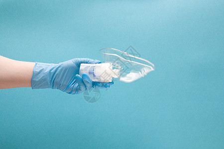 蓝色一次性医疗手套中的女性手握着含有硅胶面罩 吸入装置 肺学概念 蓝背景 复制空间的阻燃剂药库药品呼吸器治疗药剂处方感冒女士支气图片
