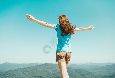 站在天空和山地背景上 举起手来的女人图片