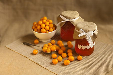 黄色樱桃李子黄果酱 新鲜果子水果 在玻璃罐中以棕色纺织品为背景的自制马铃薯图片