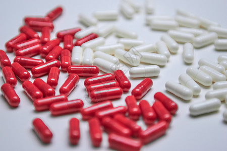 许多白色和红色胶囊药丸在丰富多彩的背景下使用 健康补充剂和药品图片