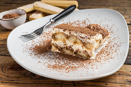 盘子里有可可的意大利蒂拉米苏蛋糕 木本背景 顶层视图食物咖啡电路甜点糕点白色巧克力奶油粉末烹饪图片