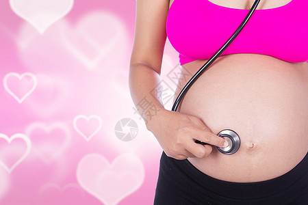 孕妇有听诊器 在心脏背面倾听肚子和婴儿的心跳图片