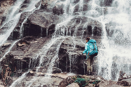 背包装妇女和瀑布远足旅行探险家冒险享受背包两极岩石游客女孩图片