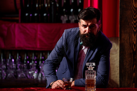 酒保豪华饮料概念 留着胡子的男人在酒吧里拿着一杯酒 服务员调酒师穿着复古背心 托盘上放着威士忌或苏格兰威士忌图片