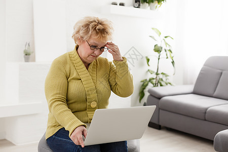 在家使用笔记本电脑工作的老妇人 祖母使用笔记本电脑并在互联网上搜索商业冲浪沙发屏幕技术互联网老年女性专注学习图片