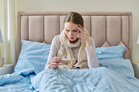 手上有温度计 坐在家中床上躺在床上的患病青年妇女症状卫生毯子过敏药品温度卧室保健痛苦发烧图片