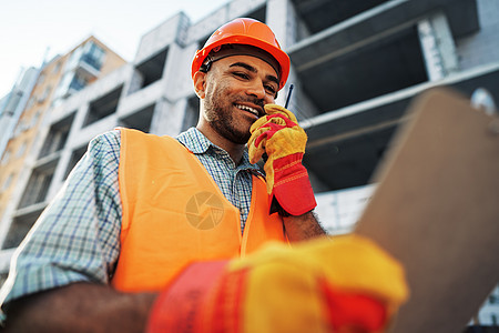 身着制服的年轻建筑工人 在现场使用对讲机安全帽安全房子建筑师领班承包商成功工程师建设者工作图片