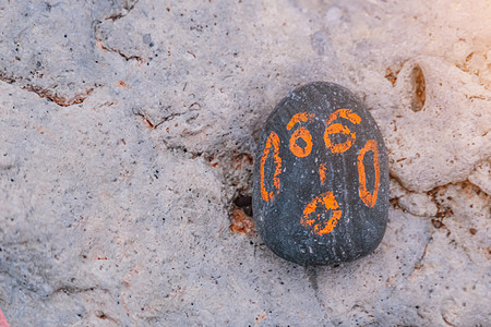 灰色鹅卵石 涂有橙色的笑脸 在一块小石头上有一张幸福的脸 概念图片