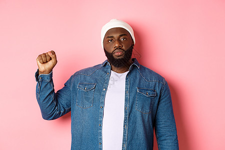 严肃而自信的非裔美国男性活动家 举起拳头 支持黑人生命问题 BLM 运动 争取人权反对种族主义 粉红色背景快乐胡须冒充潮人促销横图片