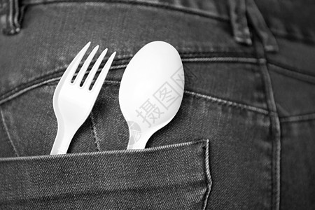 取出食物概念与蓝色牛仔牛仔裤 口袋里有白色叉子和勺子 口袋里有可重复使用的塑料勺子和叉子 安全环境和快餐概念工作室牛仔布剪裁摄影图片