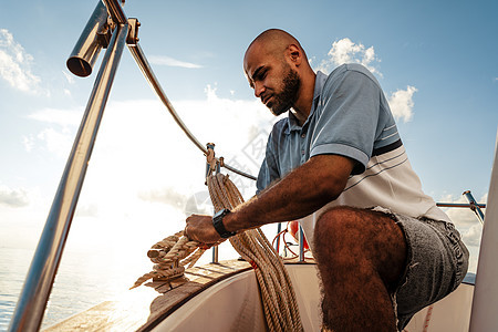 日落时 美国年轻水手在海上帆船上绑绳子帆船赛成人航程巡航海洋甲板港口血管人员旅行图片
