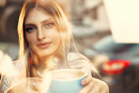 一个年轻女子的肖像 喝杯咖啡 透过窗户看望着她的身影闲暇享受朋友女孩饮料玻璃餐厅咖啡店快乐成人图片
