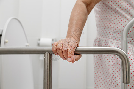 把手五金老年妇女在厕所的手扶机上栏杆机动性皱纹老化扶手病人人员退休卫生间女性背景