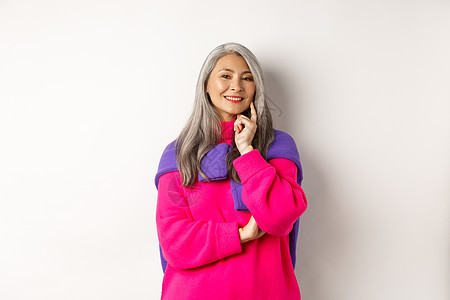 时尚的亚洲中年妇女 头发灰色 笑着高兴和深思熟虑 有想法 站在白色背景之上微笑快乐乐趣广告毛衣派对喜悦母亲化妆品女性图片