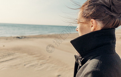 穿着大衣的女人在岸上走路图片