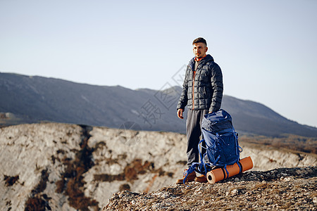 在山顶站立的徒步旅行设备中的男性背包男旅游远足登山者耐力男人运动背包农村活动天空图片