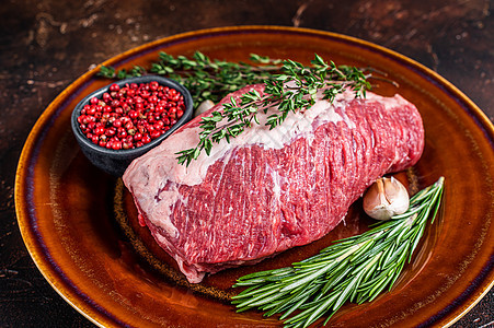 生牛肉肉 烧在有草药的生锈盘子上 深色背景臀部屠夫食物圆形红色鱼片腰部黑色酒吧大理石纹图片