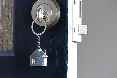用钥匙和家居形状的钥匙扣打开新家的大门 和新房概念图片
