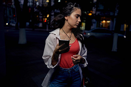 妇女用手机在户外活动 夏季走着生活方式技术女性太阳幸福街道女孩们商业城市照片摄影师图片