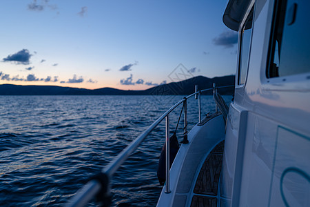 日落时在公海航行的白色游艇甲板旅游阳光运输金属探索运动海洋假期血管旅行图片