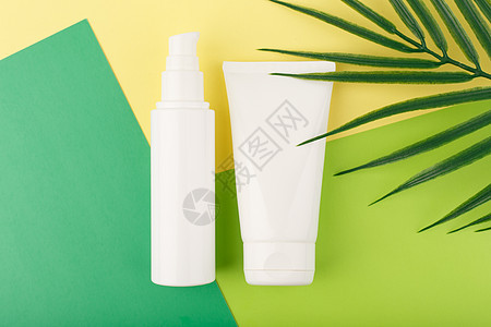 含有棕榈叶的绿纸和黄纸上的白色无品牌管状白钢丝中的化妆品商品护理皮肤团体凝胶瓶子淋浴浴室卫生产品图片