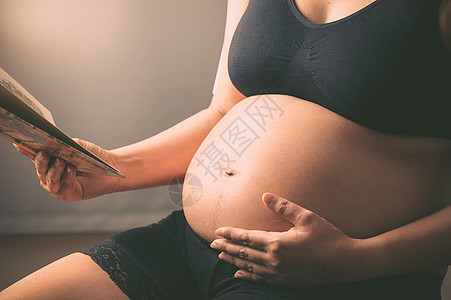 正在阅读一本书的孕妇母亲妈妈孩子拥抱产妇医疗生活方式怀孕生长女士图片