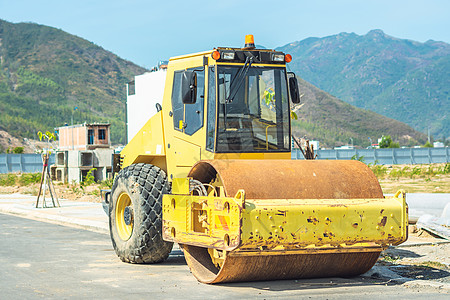 在蓝天下新建现代多层建筑区道路施工现场的大黄色压路机的大视野 民用建筑业图片