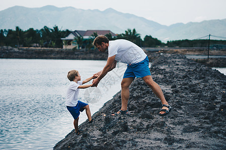 爸爸帮助儿子下湖水 解释安全规则 晚上 山背景 快乐的童年父亲 一家人一起散步玩耍 家庭自然教育 父亲节 责任图片