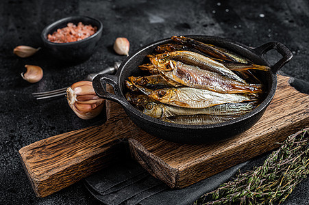 烧热的烟熏斑鱼和锅中鱼尾鱼 黑色背景 顶层视图图片